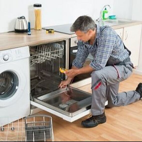 Dishwasher repairman holding a volt meter and fixing a counter built in dishwasher