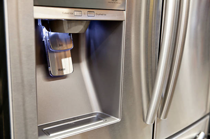 Close up of a silver samsung refrigerator showing a water and ice dispenser with blue light illuminating the fridge