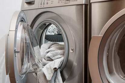 A bronze samsung washer repair with white towels piled up in a slightly open  washer door